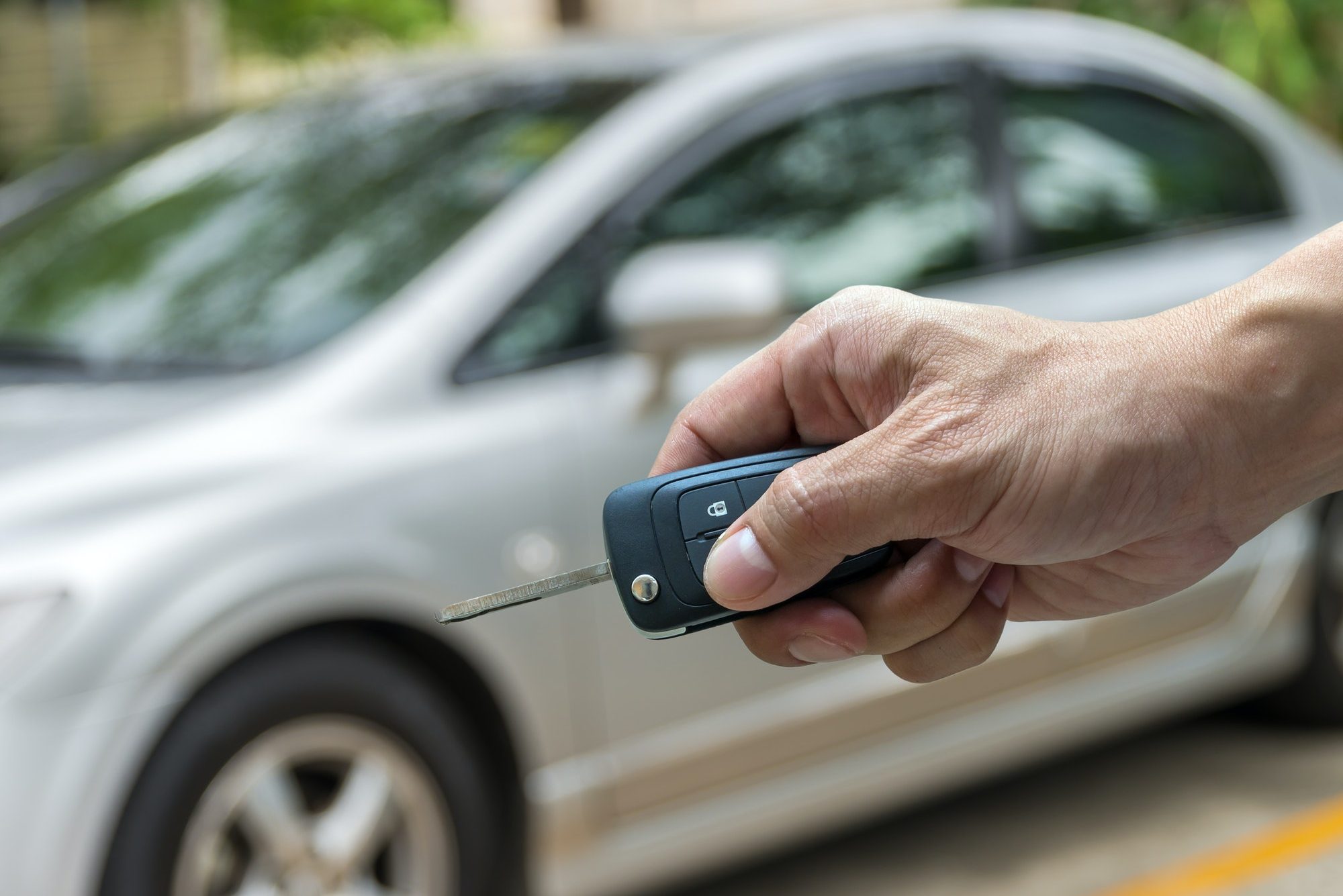 Hand holding the keys over photo blurred of used car for open the door car,