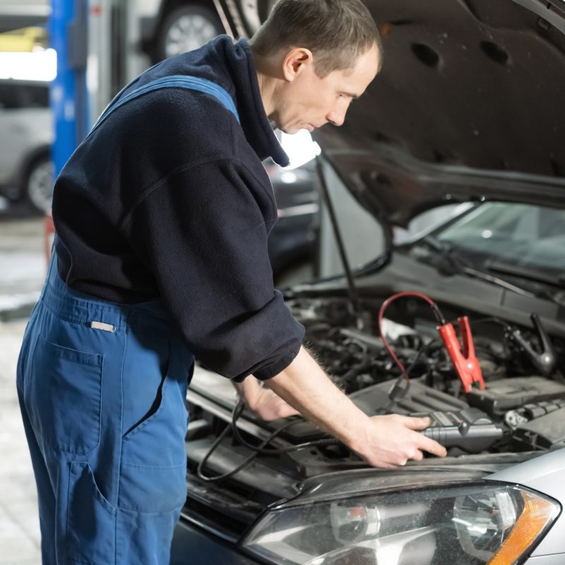 Mechanic examining car under the hood at the repair garage.